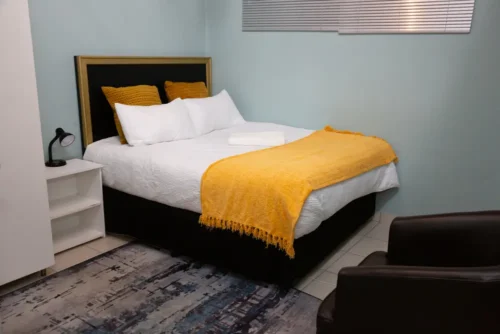 Bed, bedside lamp and a dark armchair in the Single Room.