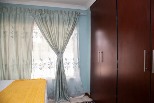 Built-in dark wood wardrobe beside the window in the Single Room.