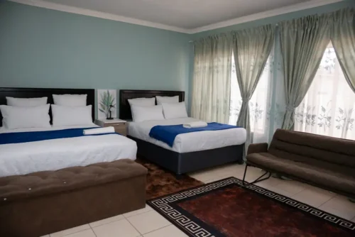 Two double beds, a sofa and wide curtained windows in the Family Room.