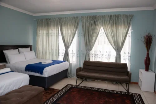 The Family Room seen from the door: two beds, a brown sofa under the windows and a patterned rug.